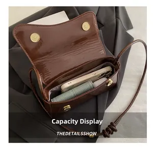Detail view showing the internal capacity of the brown patent leather crossbody bag
