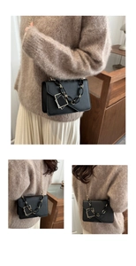 Detail view of black faux leather handbag with gold geometric buckle and chain