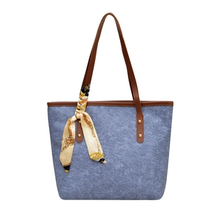 Blue canvas tote bag with brown leather handles and decorative silk scarf accessory