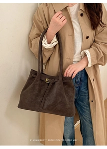 Detail of vintage brown tote bag with metal buckle on khaki trench coat look