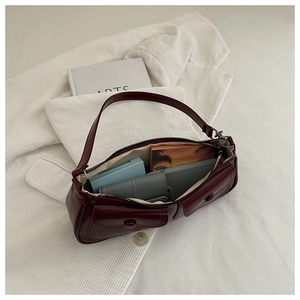 Top view of deep red glossy leather shoulder bag showing interior space and pocket details