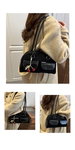 Close-up of black Boston bag with glossy flap pockets and a gold cherry charm detail