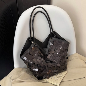 Large black sequin tote bag with V-cut top and slim shoulder straps on a white chair