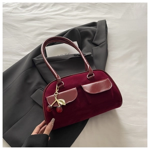 Detail of vintage burgundy velvet handbag with twin pockets and cherry charm