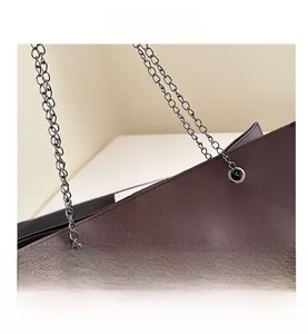 Détail du cuir grainé marron foncé et de la fixation de la bandoulière en chaîne