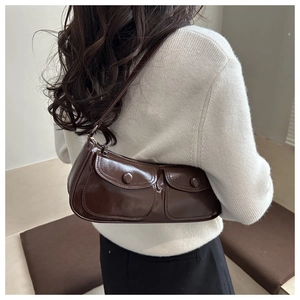 Model wearing dark brown patent leather underarm bag with double front flap pockets