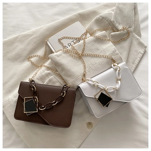 Flat lay of brown and white crossbody bags with chunky chain and gold shoulder straps