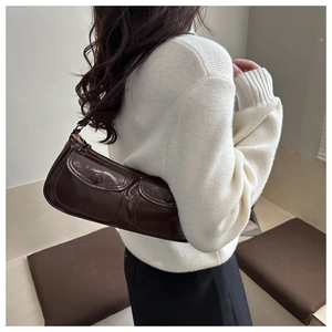 Detail of dark brown patent leather crescent bag with double front flap pockets