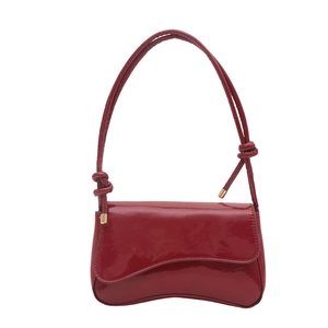 Glossy red patent leather underarm bag with asymmetrical flap and knotted shoulder strap