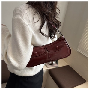 Detail view of burgundy patent leather shoulder bag with dual flap pockets and metal chain