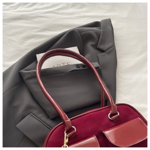 Detail of dark red suede and leather shoulder bag with two front pockets and gold hardware