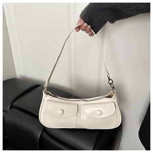 Détail du sac crème avec deux poches frontales et bandoulière avec maillons métalliques