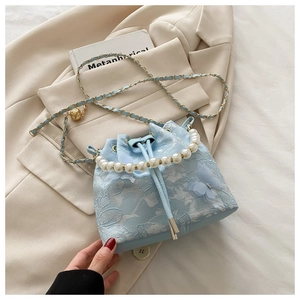 Détail du sac seau en dentelle bleu clair avec papillons 3D et anse en perles