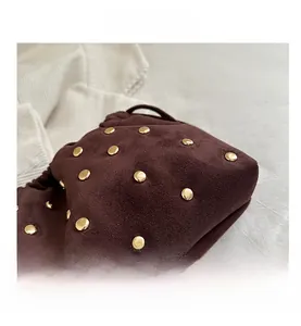 Dettaglio borsa in pelle scamosciata marrone con borchie dorate e texture in pelle morbida