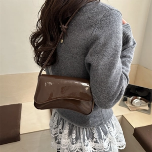 Minimalist deep brown patent leather underarm bag with curved flap and knotted strap