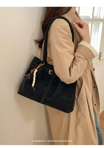 Detail of black suede tote bag with ethnic wooden beads and metallic buckle strap