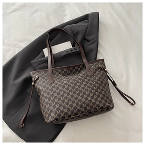 Close-up of vintage monogram pattern and brown leather straps on a large tote bag