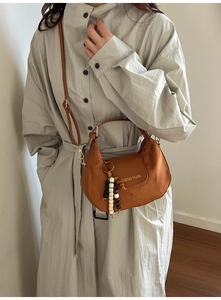 Brown suede crescent bag with a wooden bead charm and adjustable leather strap