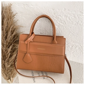 Close-up of brown crocodile embossed texture and gold fashion logo on vintage handbag