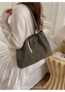 Detail view of dark grey vintage tote bag with beaded charm and leather buckle strap