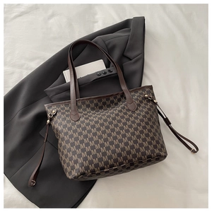 Detail of a brown tote bag featuring vintage M-pattern monogram and side drawstring accents