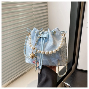 Détail du sac seau bleu clair avec papillons 3D, poignée perle et chaîne dorée