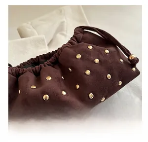 Dettaglio pochette in camoscio marrone con borchie dorate e chiusura a coulisse