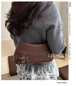 Detail of a brown leather shoulder bag with vintage silver buckle and strap accents