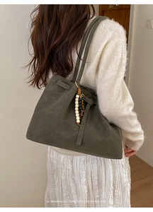 Detailed macro of dark olive green retro tote bag with artful beaded charm and leather strap