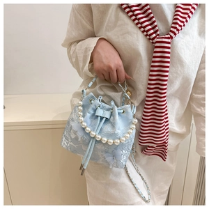 Détail d'un sac seau bleu clair avec dentelle florale blanche et papillons 3D décoratifs