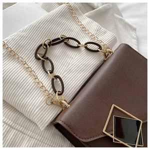 Detail of brown square crossbody bag with gold hardware and resin chain link