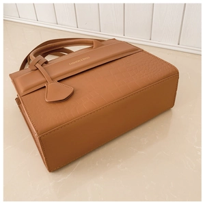 Detail of tan crocodile embossed leather handbag with fashion text and sturdy round handles