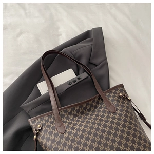 Detailed macro of vintage M-pattern printed tote bag with golden hardware and leather straps