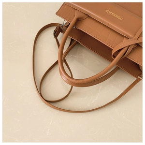 Close-up of brown crocodile pattern handbag with golden logo and top handle detail
