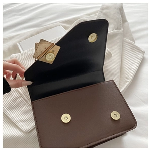 Detail view of the magnetic closure and dual-tone leather interior of the crossbody bag