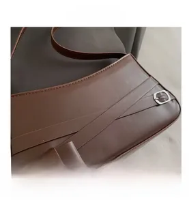 Close-up of brown leather bag featuring criss-cross straps and silver oval buckles