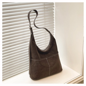 Detail of dark brown Hobo tote bag featuring white contrast stitching and front pockets