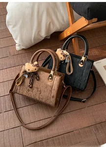 Detail of corduroy and leather shoulder bags with plush pendant and metal hardware