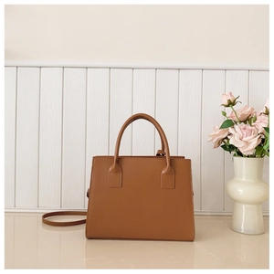 Detailed view of brown stone-pattern leather tote bag on beige surface with a floral vase