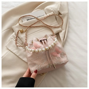 Détail du sac seau en dentelle rose avec papillons 3D et élégante poignée en perles
