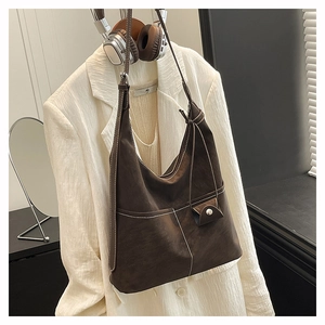 Detail of dark brown matte tote bag with contrast white stitching and mini charm