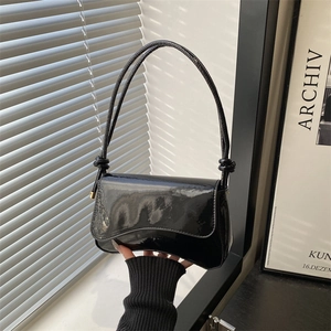 Minimalist black patent leather underarm bag with knotted strap and sleek curved design