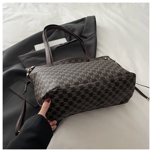 Detail of vintage monogram jacquard fabric on a large capacity tote bag with brown straps