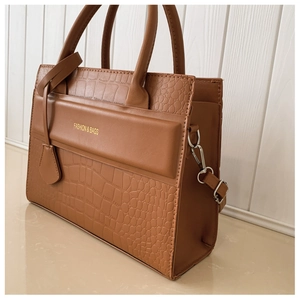 Detail of vintage brown shoulder bag showing golden logo and croc-embossed texture