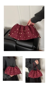 Dettaglio borsa a secchiello in camoscio rosso scuro con borchie dorate e coulisse