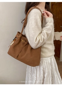 Close-up of retro brown frosted suede tote bag with wooden bead charm and metal buckle detail