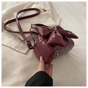 Macro detail of wine red cylinder bag with leather bow and silver star studs