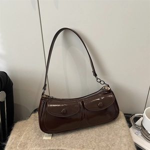 Dark brown leather shoulder bag with double pockets and metal chain on a cozy knit background