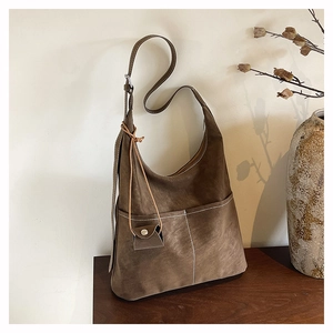 Detailed view of dark brown suede tote bag with contrast white stitching and mini charm
