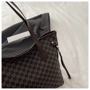 Detailed macro view of large tote bag with vintage M-letter print and gold metal buckles